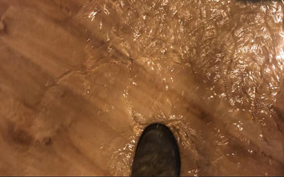Top down image of a foot walking thru flooding water caused by burst pipe