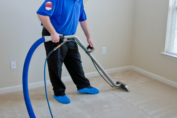 Man cleaning a residential carpet with commercial steam cleaning equipment